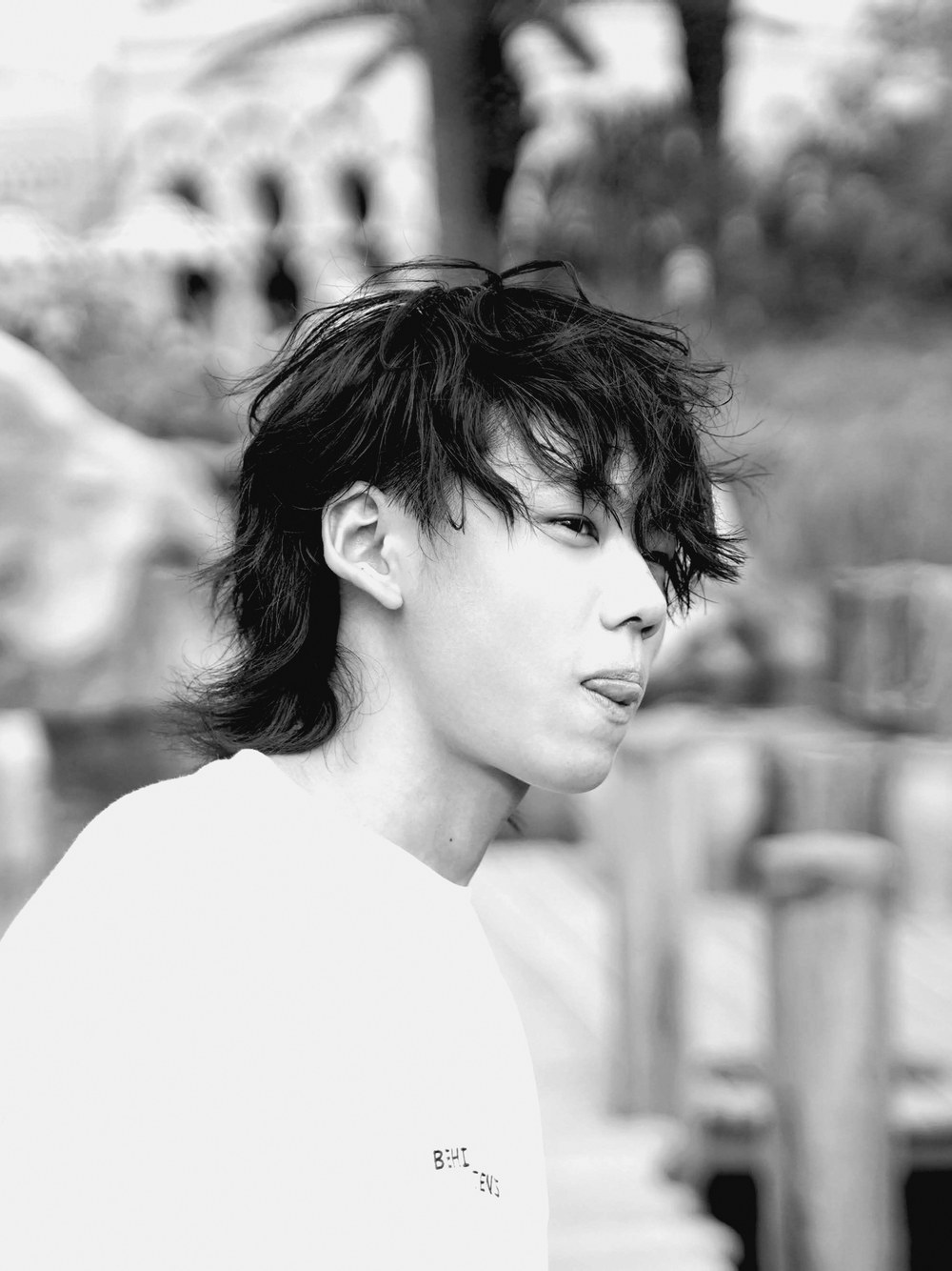 tenqboy のアーティスト写真。白い背景に、風で乱れた髪の横顔。